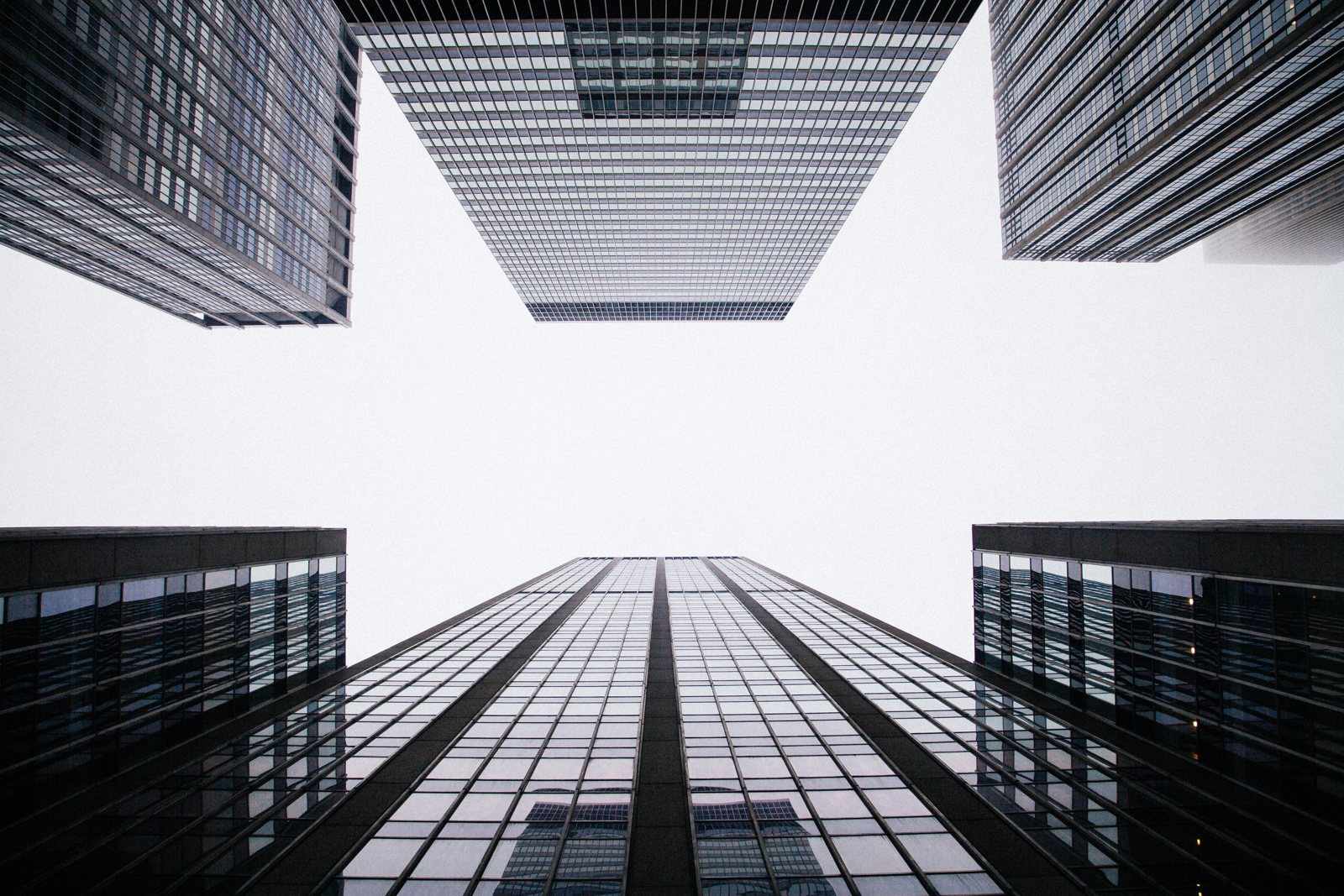 Glass office towers seen from street level, looking straight up between them